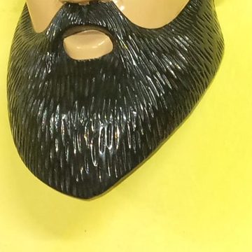 Acercamiento a una barba negra tallada en madera con incisiones que imitan el pelo