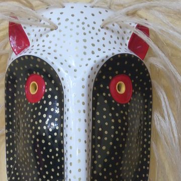 Acercamiento a la máscara del nahual blanco: discos negros y rostro blanco cubiertos de puntos dorados, ojo rojo