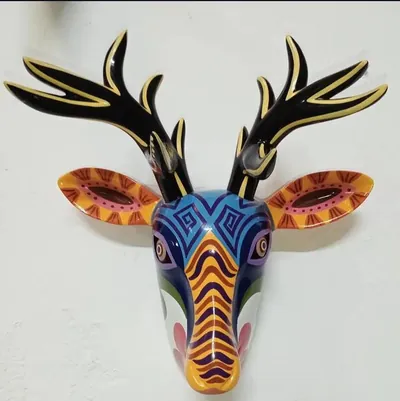 Máscara de venado con astas negras, orejas anaranjadas y rostro azul con grecas y franjas onduladas