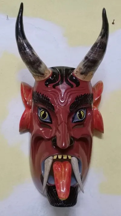 Máscara de diablo rojo oscuro con cuernos largos, orejas puntiagudas, colmillos y lengua roja de fuera