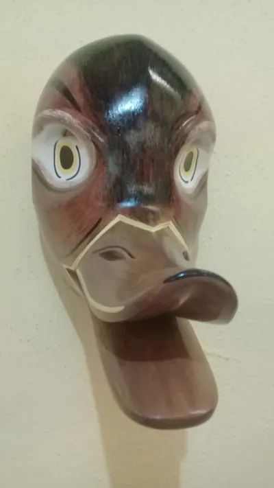 Máscara de pato en tonos cafés con ojos grandes blancos y pico ancho saliente