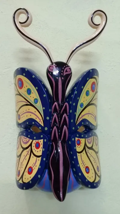 Máscara de mariposa con alas azul marino y amarillas, cuerpo morado como nariz y antenas enroscadas