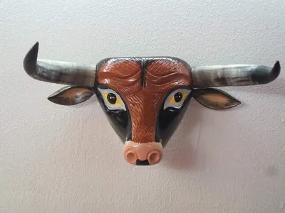 Máscara de toro café rojizo con pelo tallado, ojos amarillos, cuernos grises y hocico rosado