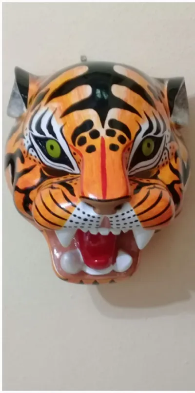 Máscara de tigre anaranjado con rayas negras, ojos verdes y colmillos, de frente