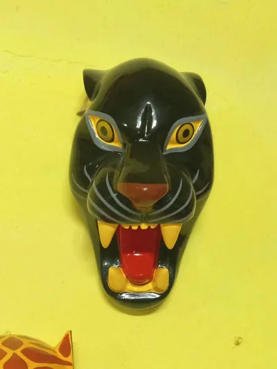 Máscara de pantera negra con ojos amarillos, bigotes grises y hocico rojo abierto con colmillos amarillos