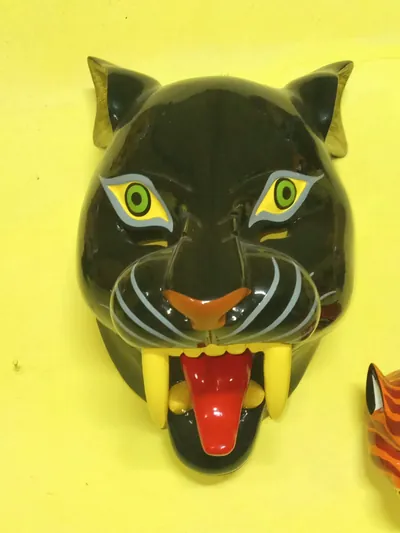 Máscara de pantera negra con ojos verdes, nariz anaranjada, colmillos amarillos y lengua roja