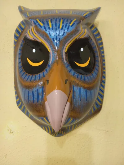 Máscara de búho azul con pincelado café, grandes ojos negros con media luna amarilla y pico rosado