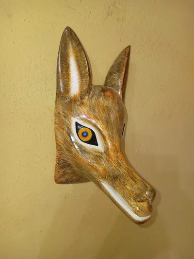 Máscara de lobo de estilo realista con pelaje ocre y café a pinceladas, orejas altas y ojo ámbar, vista de tres cuartos