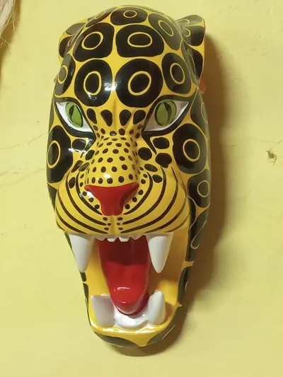 Máscara de jaguar amarillo con rosetas negras, ojos verdes y boca abierta con colmillos blancos