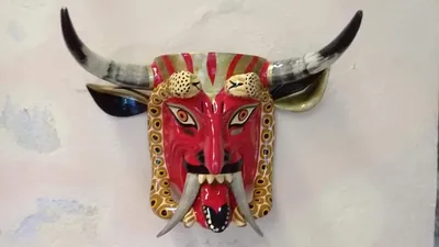 Máscara de diablo rojo con cuernos de toro, colmillos largos, lengua de fuera y marco amarillo con círculos