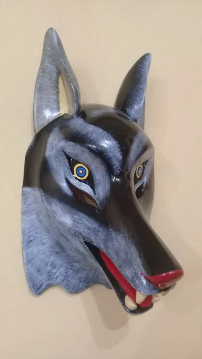 Máscara de lobo gris y negro con orejas puntiagudas, ojos azules y amarillos y hocico abierto con colmillos