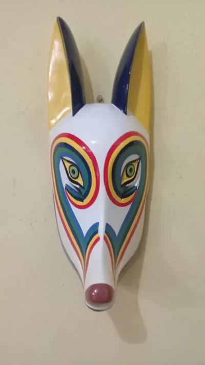 Máscara de coyote blanco con franjas de arcoíris alrededor de los ojos, orejas amarillas y nariz rojo oscuro