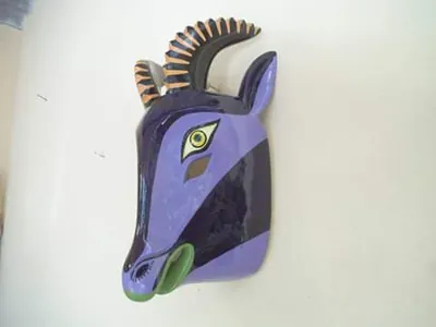 Perfil de máscara de chiva morada con cuernos curvos rayados y hocico verde