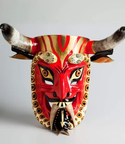 Máscara de diablo roja con cuernos grandes, colmillos y lengua negra con flecha dorada