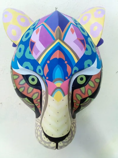 Máscara de jaguar multicolor con diseños geométricos y florales en azul, morado, rosa y anaranjado