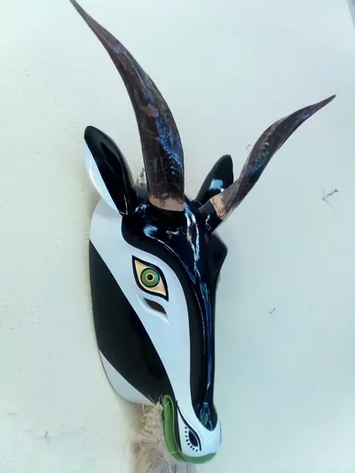 Máscara de chiva blanca y negra con cuernos largos color café, ojos verdes y barba de fibra