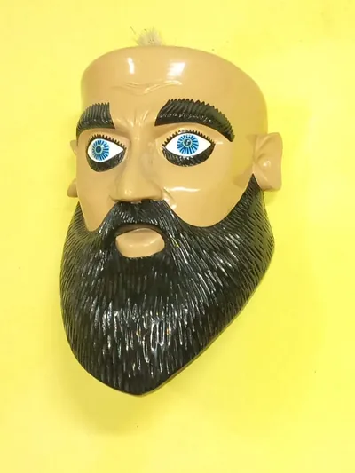 Máscara de hombre de piel clara con barba negra tallada y ojos azules sobre pared amarilla