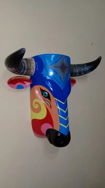 Máscara de toro azul con cuernos oscuros, hocico negro y un costado anaranjado con espiral amarilla