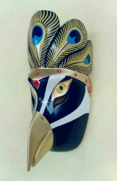 Máscara de ave azul marino con pico dorado y penacho de plumas de pavo real