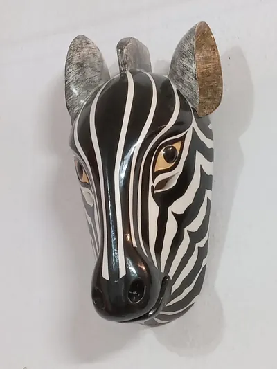 Máscara de cebra de franjas negras y blancas con ojos color miel sobre pared blanca