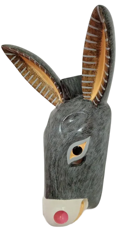 Máscara de burro gris con orejas largas rayadas y hocico blanco con fosas rosas, vista de perfil en pared blanca